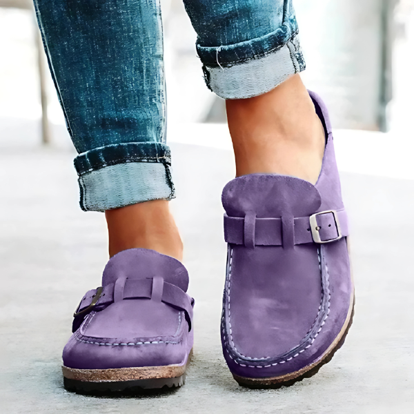 Purple loafers worn with rolled-up jeans on a light background