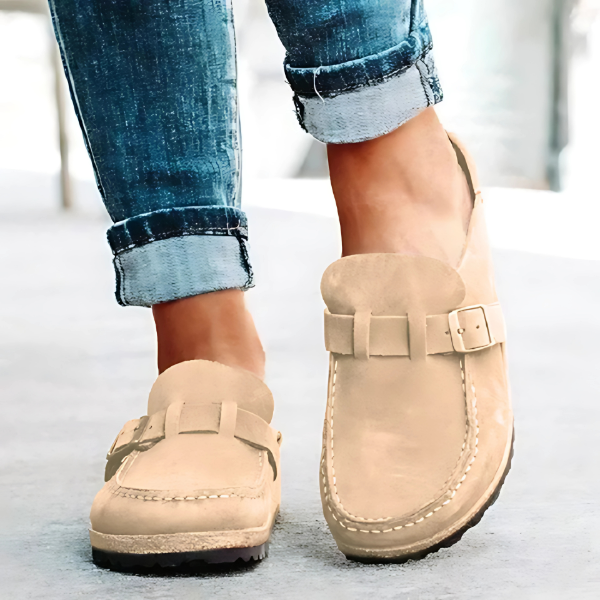 Beige loafers worn with rolled-up jeans on a light background