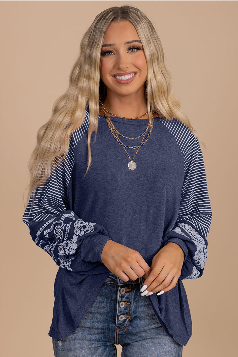 Woman wearing a blue long-sleeve top with lace details on a beige background