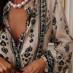 Person wearing a black and white patterned blouse with pearl necklace