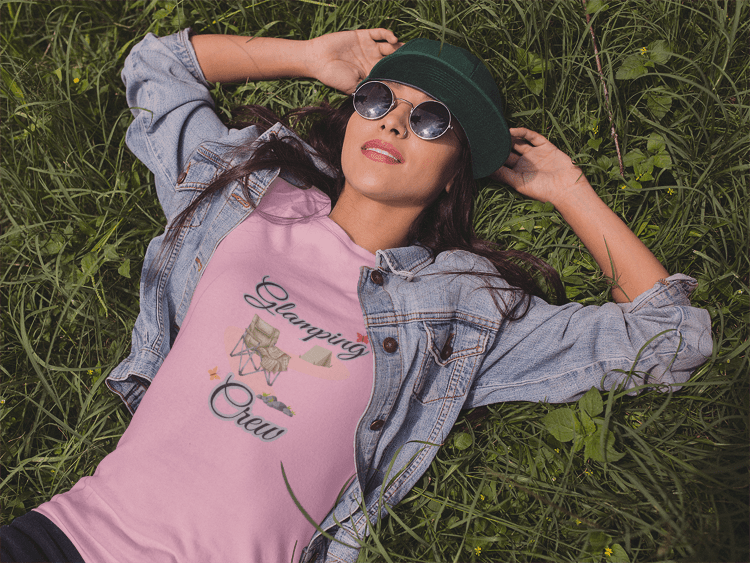 Woman wearing a pink t-shirt with text and graphics, lying on grass