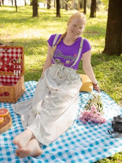 Person sitting on a picnic blanket with a basket and cake in a park