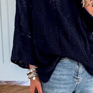 Person taking a mirror selfie wearing a navy sweater and light blue jeans in a room with wooden flooring.