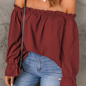 Red off-shoulder top worn by a person against a gray background