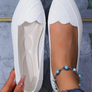 White flat shoes with a close-up of the sole and a foot wearing a anklet.