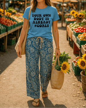 Woman at an outdoor farmers market wearing a blue t-shirt with a message and holding sunflowers.