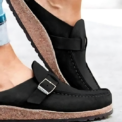 Black sandals with cork sole worn by a person on a light background