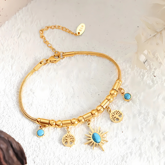 Gold bracelet with turquoise charms on a textured white surface