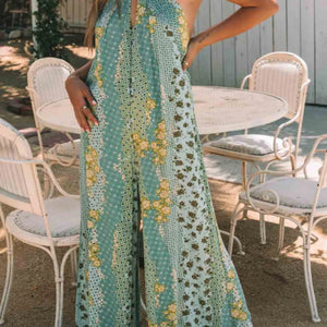 Person wearing a floral dress in an outdoor setting with chairs and tables.