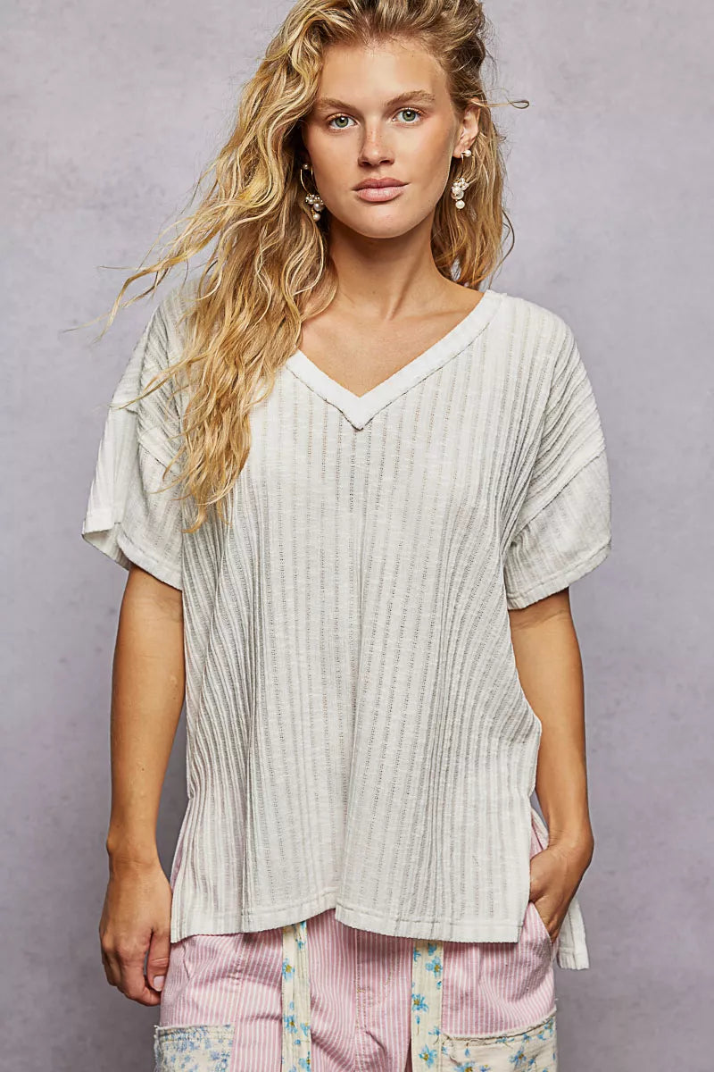 Woman wearing a loose-fitting white top against a gray background