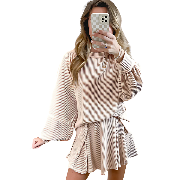 Woman wearing a beige top and skirt set taking a mirror selfie.