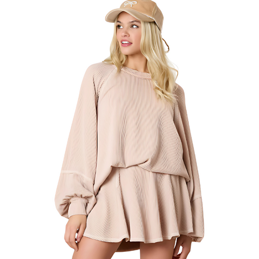 Woman wearing a beige top and skirt set and cap on a white background