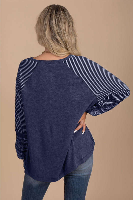 Navy blue long-sleeve top with striped sleeves worn by a person on a beige background