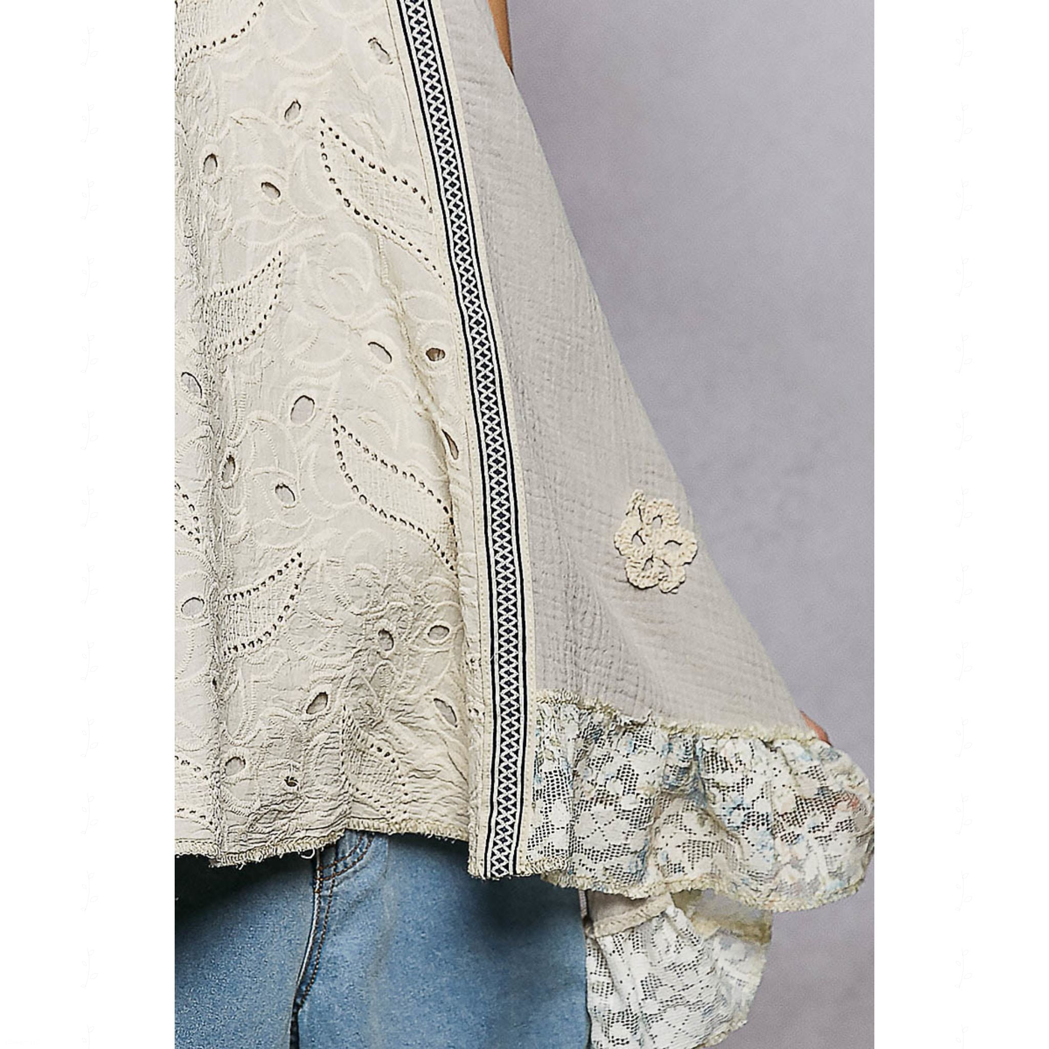 Light-colored lace top with floral details on a plain background