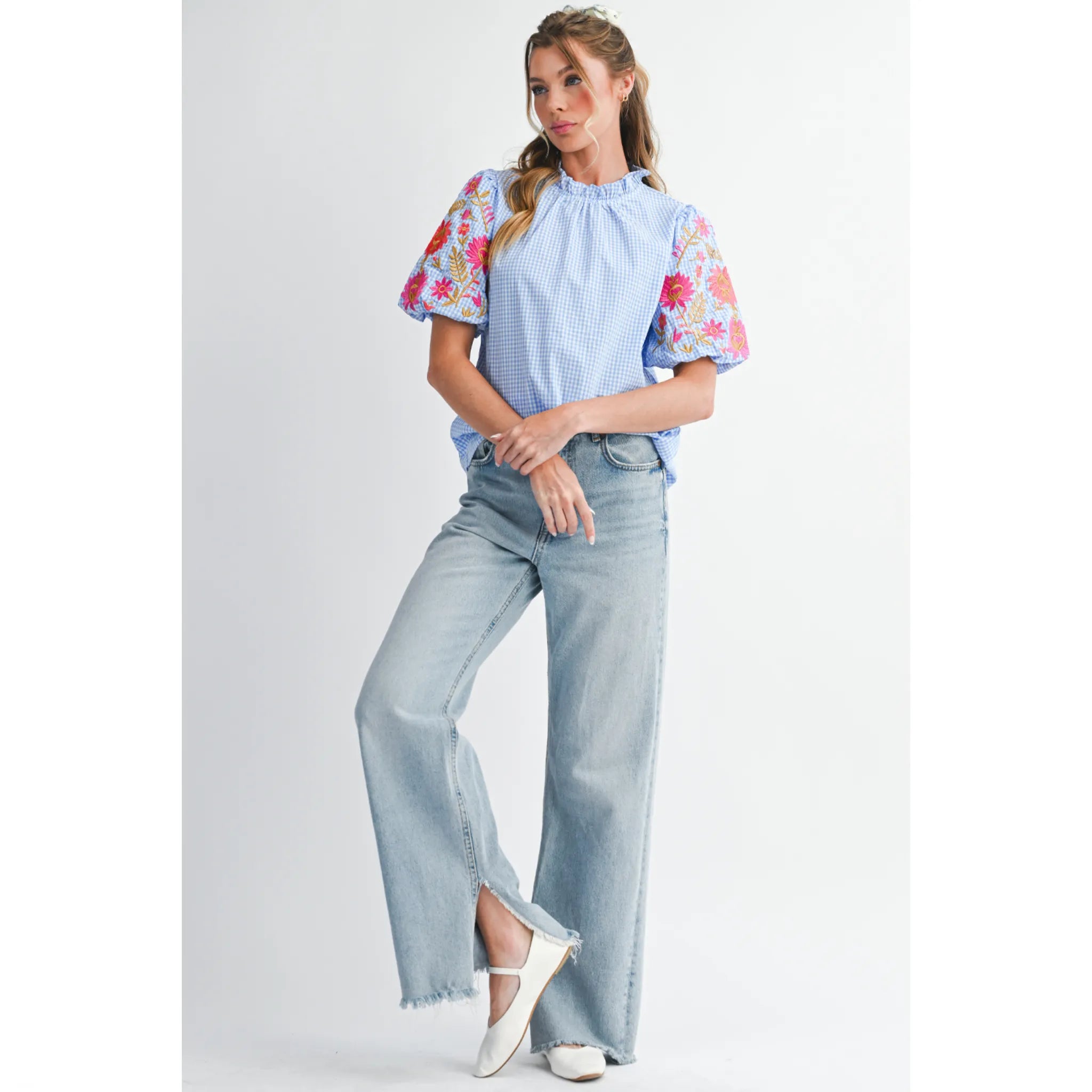 Woman wearing a floral blouse and light blue jeans on a white background