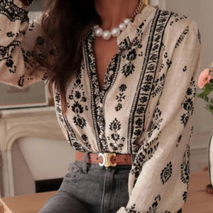 Person wearing a patterned blouse with a pearl necklace in an indoor setting