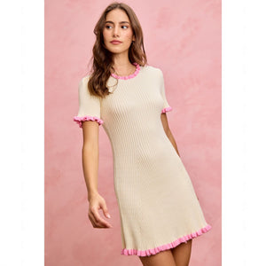 Woman wearing a white dress with pink trim against a pink background