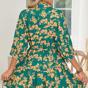 Person wearing a green and orange floral dress indoors.