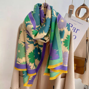 Colorful patterned scarf with green, purple, and yellow on a wooden hanger against a white background.
