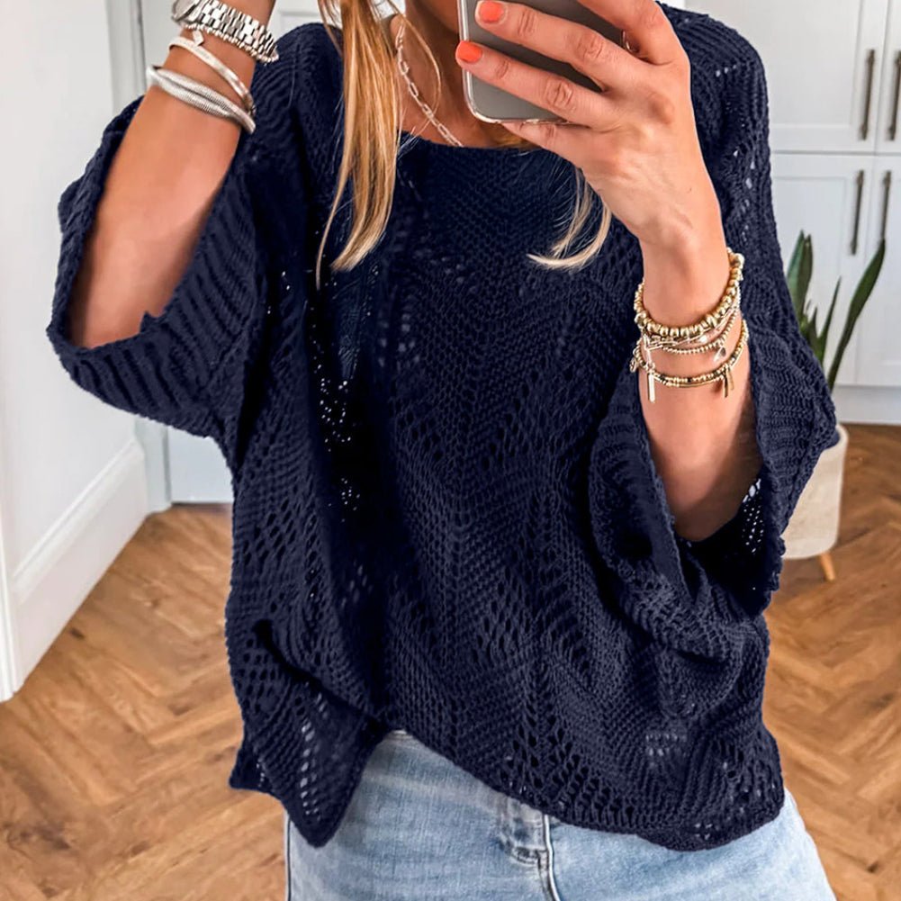 Person wearing a navy blue knitted sweater and light blue jeans, taking a mirror selfie.