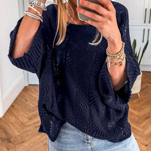 Person wearing a navy blue knitted sweater and light blue jeans, taking a mirror selfie.