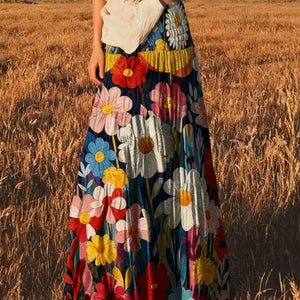 Person wearing a colorful floral dress standing in a field.