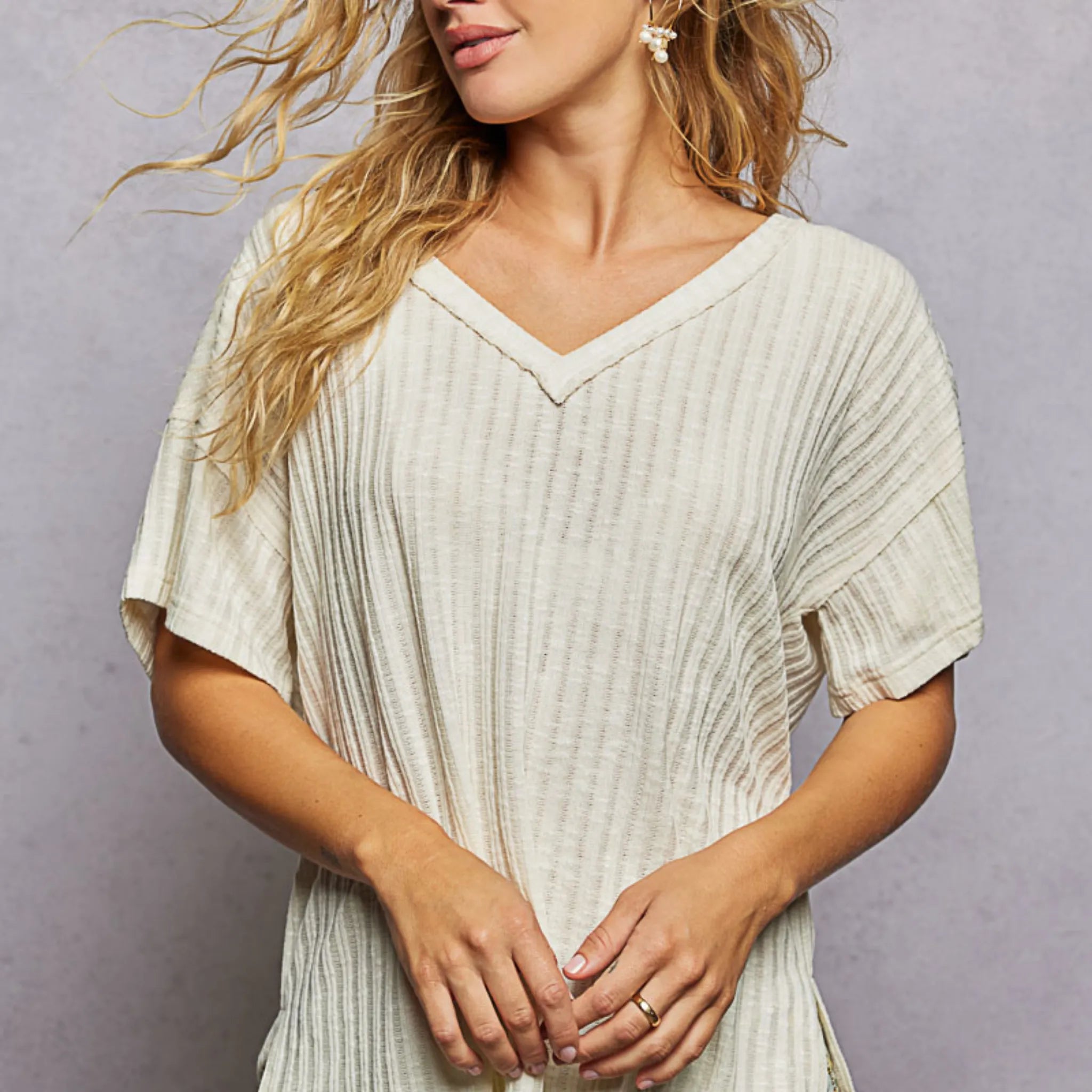 Woman wearing a beige ribbed dress against a gray background