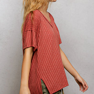 Person wearing a red patterned shirt against a plain background